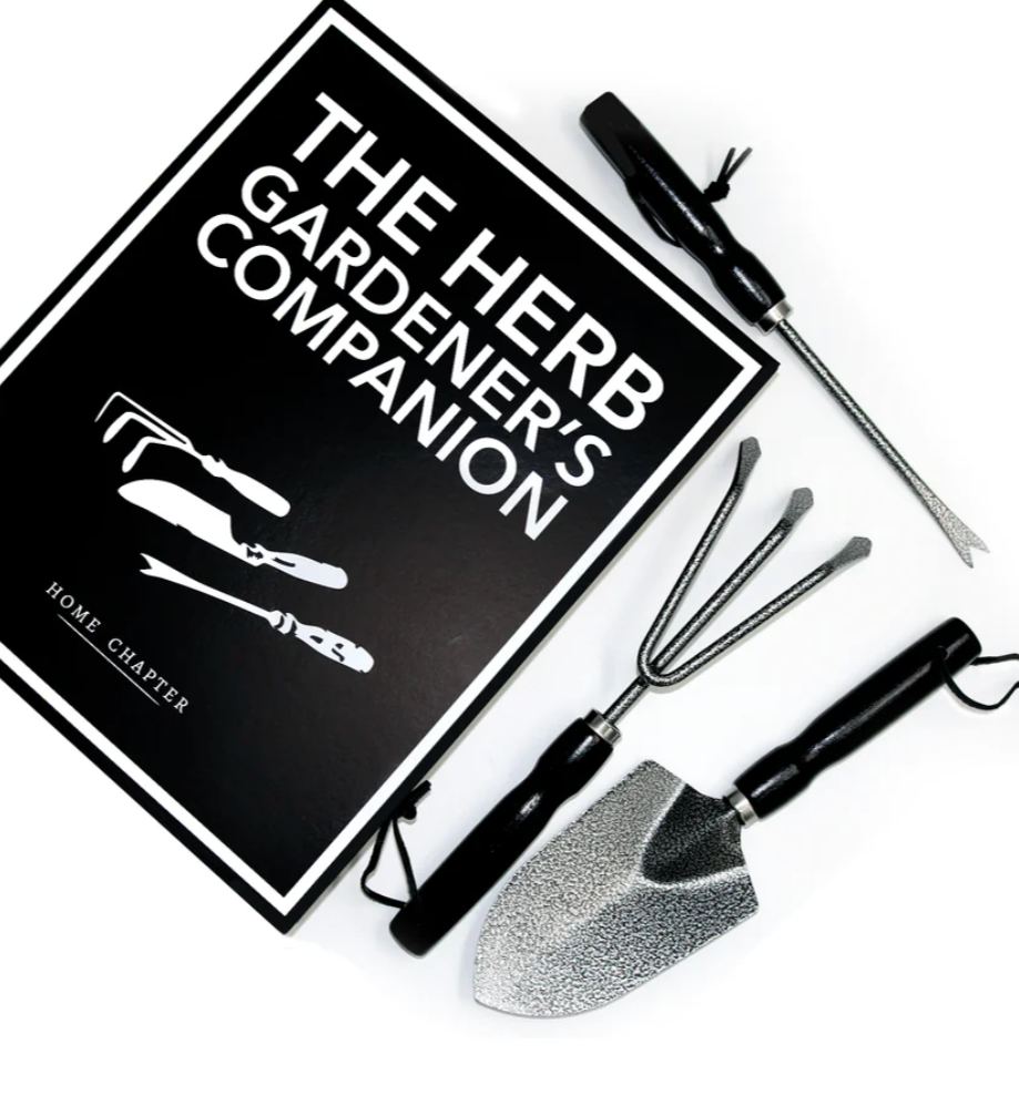 Gardening tools and 'The Herb Gardener's Companion' book on a white background